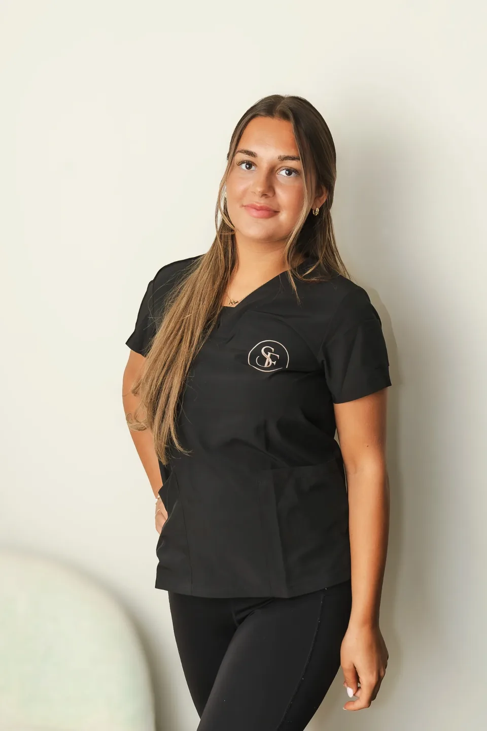 Portret van Esme, mede-oprichter en Spray Tan Specialist van Studio Eslaine in Nijmegen, in zwarte werkkleding tegen een lichte studioachtergrond